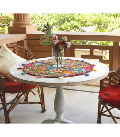 Stunning Barmer green round table runner close-up displaying handcrafted cotton embroidered patchwork with floral and leaf designs, tassels, and textured details
